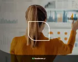 Donna con eccellenti competenze analitiche esamina grafici e dati su un grande schermo interattivo.