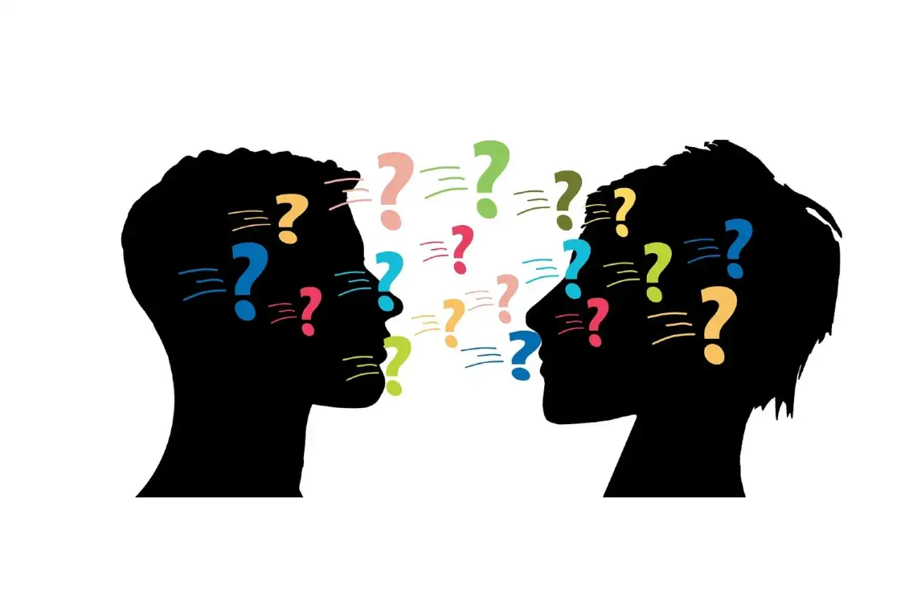 Silhouette di due teste che si fronteggiano, con punti interrogativi colorati che simboleggiano il processo di ascolto attivo in psicologia.