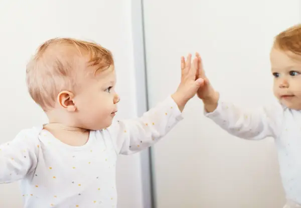 Bambino che tocca il suo riflesso, un momento chiave nella costruzione del sé nel bambino.